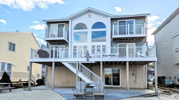 A two-story building with a balcony, a staircase, and a deck area. - Charming 4-bedroom house with WiFi and AC in tranquil Ocean Pines (Ocean Pines)