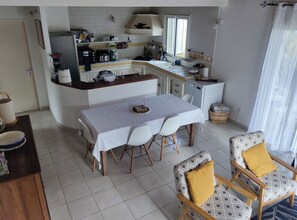 A compact kitchen with a dining area, featuring a table set for four, a small refrigerator, and a window providing natural light.