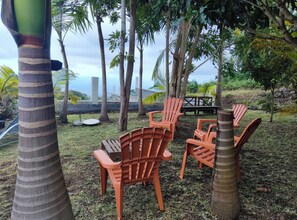 Outdoor seating with chairs and a table, surrounded by palm trees and a view of the city. - Ti kaz Annah - Cozy House with a Terrace, Volcanic Region & Nature (Le Tampon)