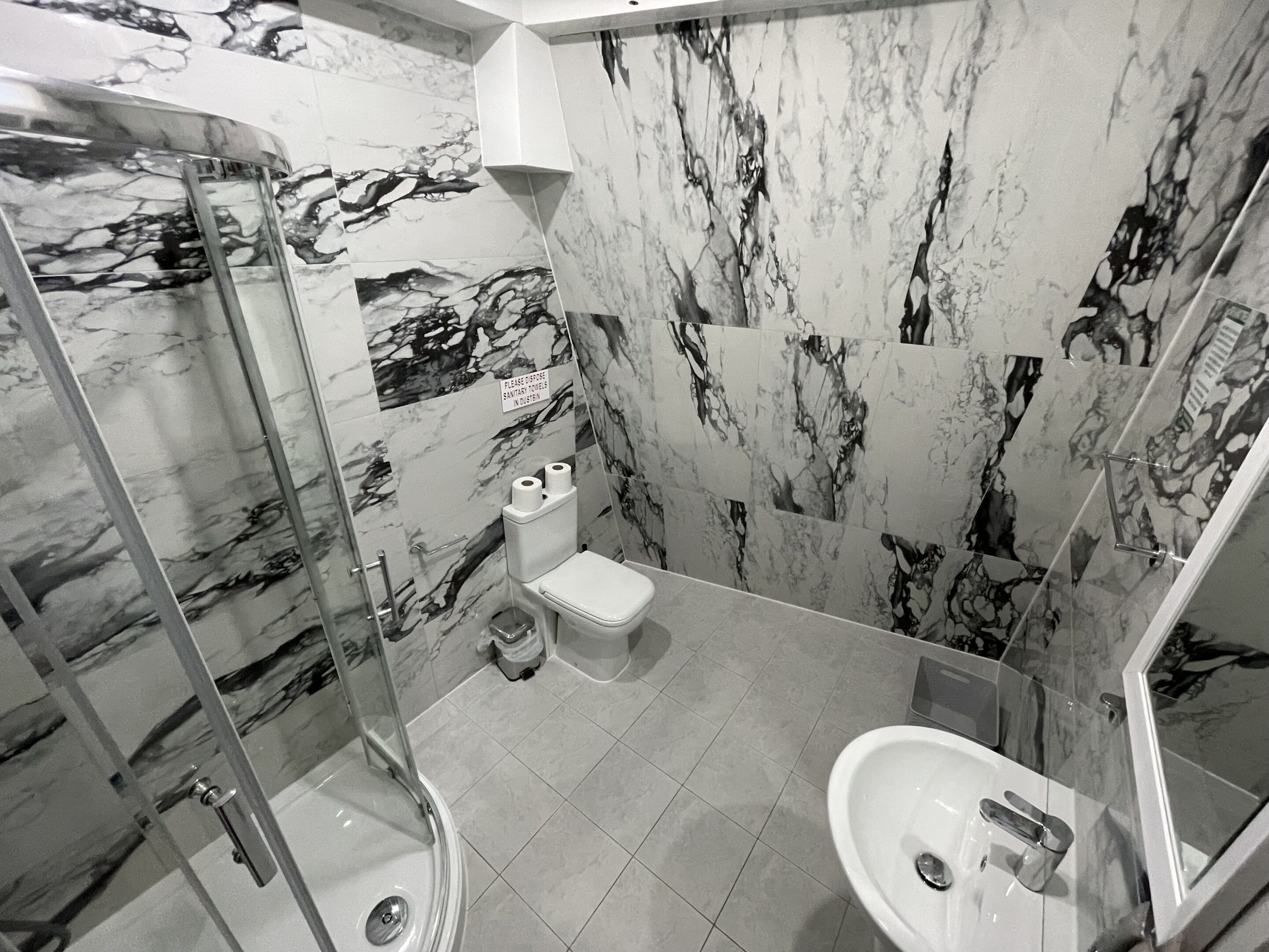 Un baño con cabina de ducha de vidrio, inodoro y lavabo.