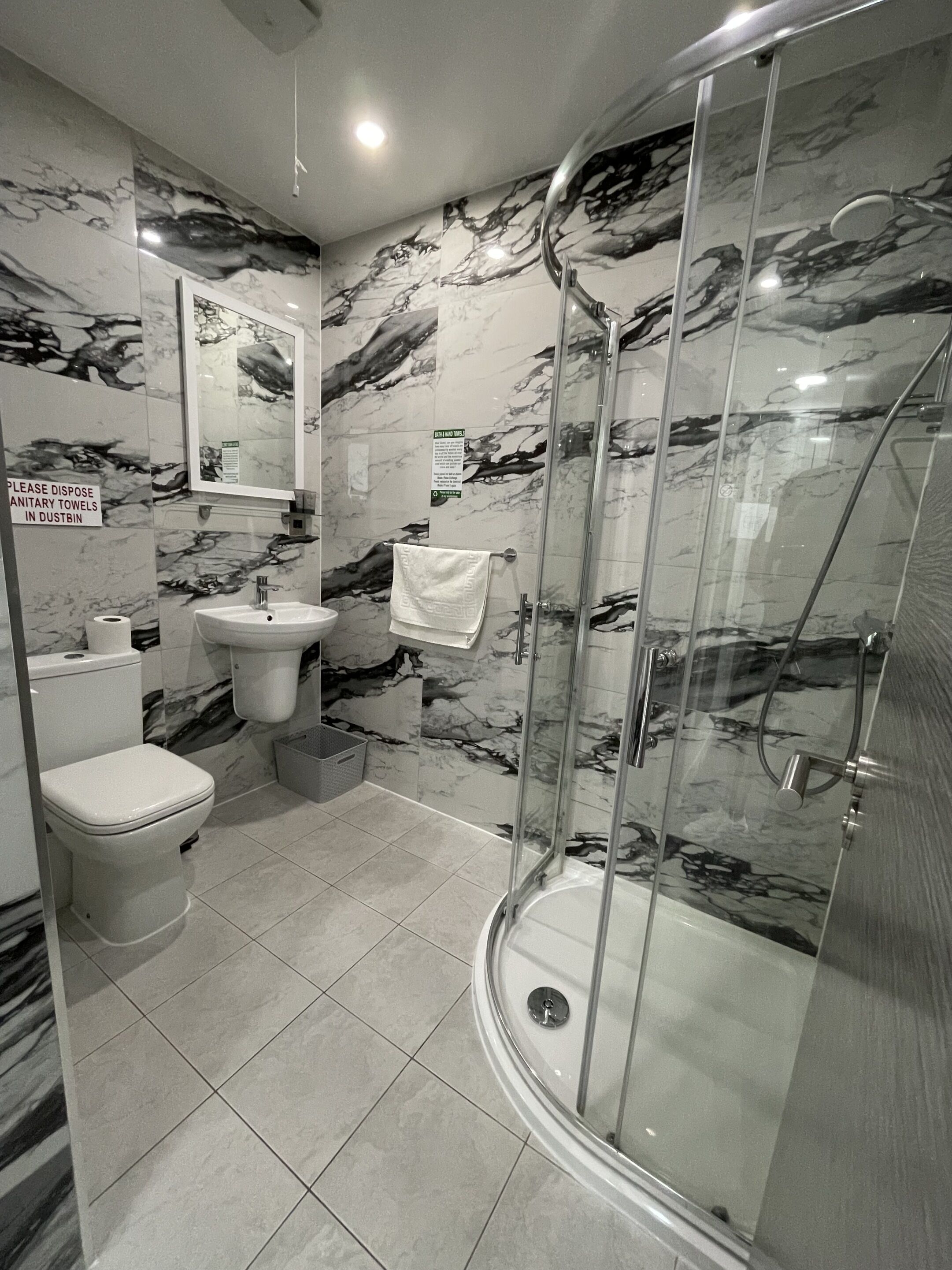 A modern bathroom with a glass-enclosed shower, a toilet, and a sink.