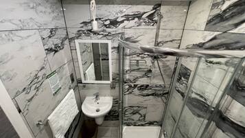 A bathroom with a glass-enclosed shower, a sink, and a mirror.