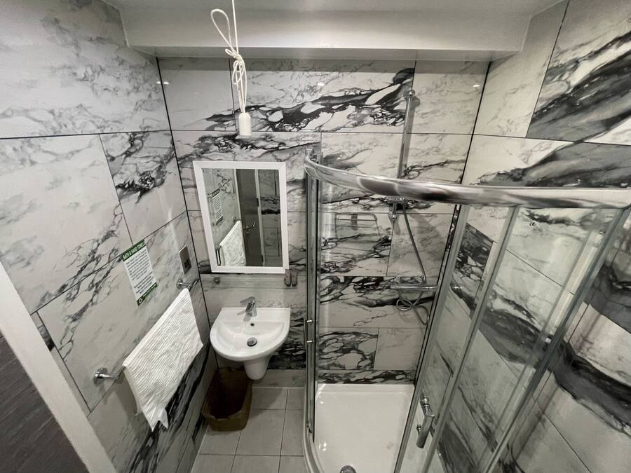 A bathroom with a glass-enclosed shower, a sink, and a mirror.