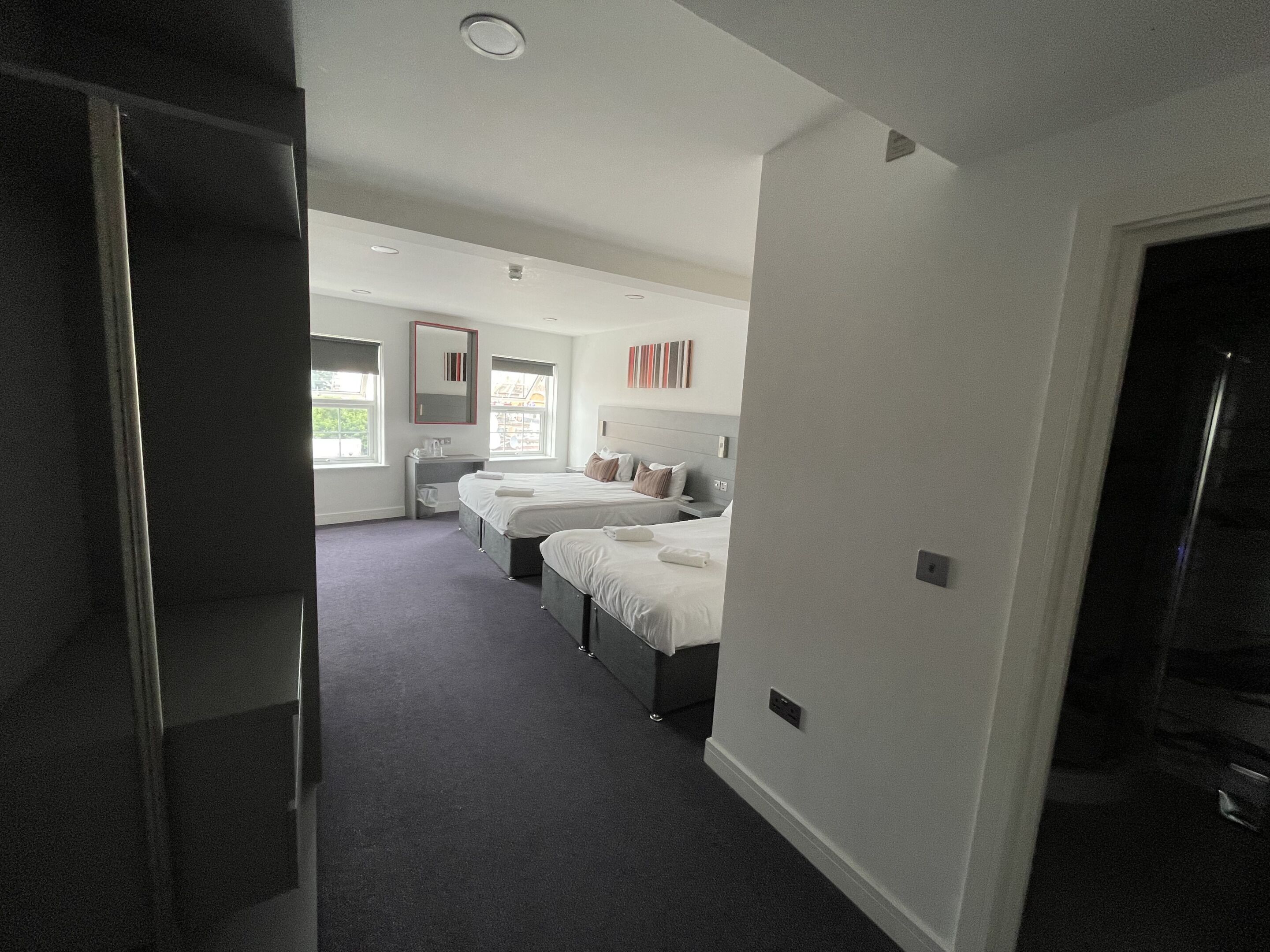 Quarto de hotel moderno com duas camas, banheiro e vista para a cidade.