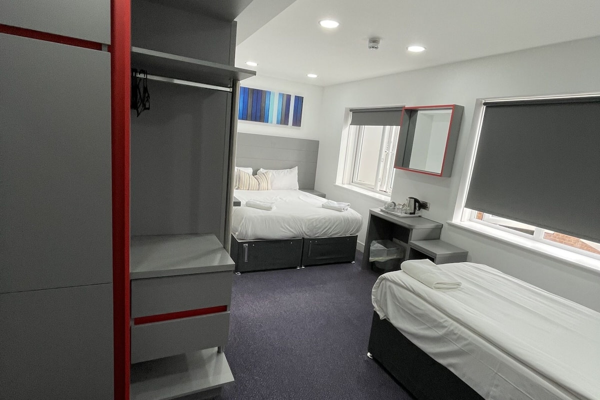 A hotel room with two beds, a wardrobe, a desk, and a window with a view.