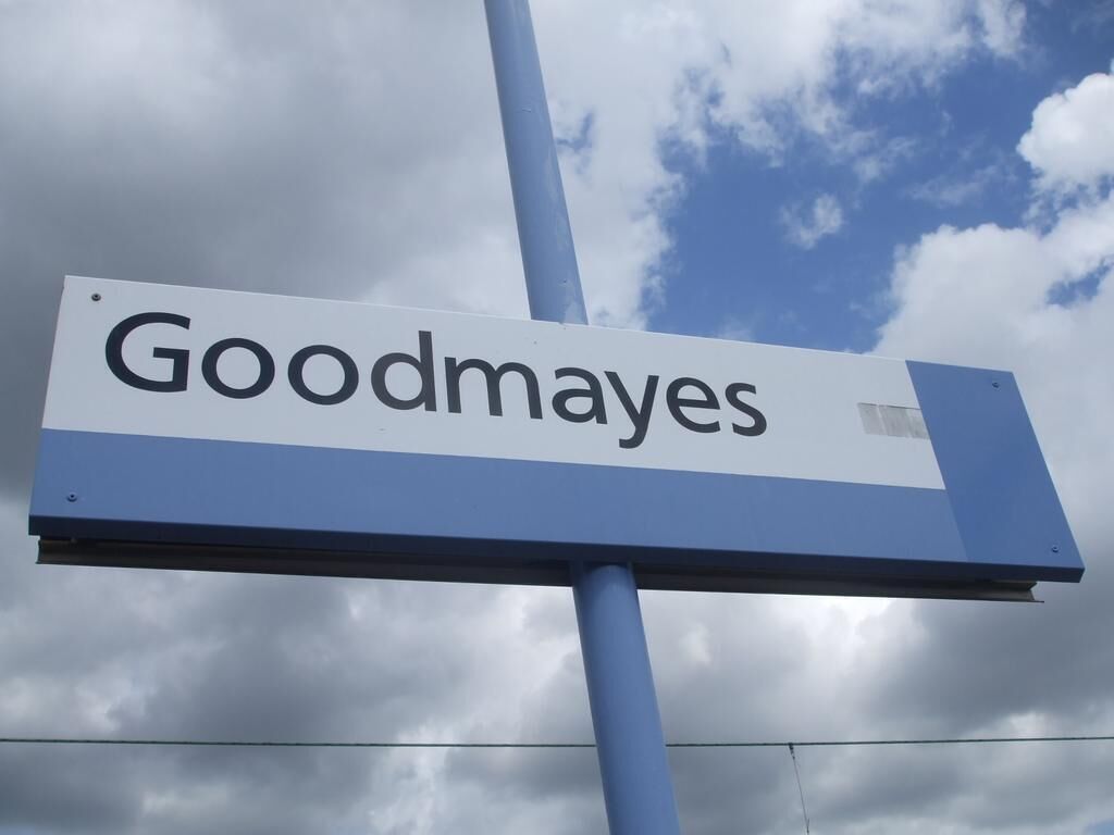 Een bord met de tekst 'Goodmays' voor een bewolkte lucht.