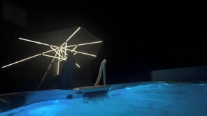 A swimming pool with a geometric light installation in the background.