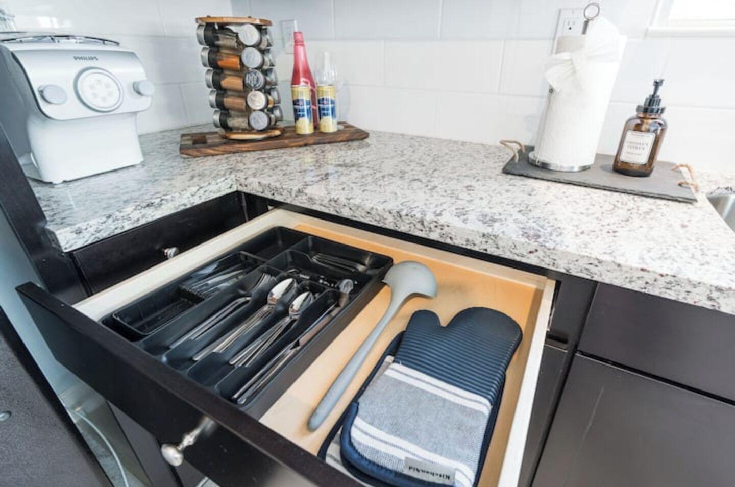 A kitchen with a drawer organizer containing utensils, a toaster, and condiments.