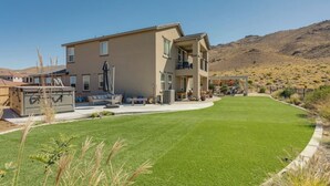 A two-story house with a flat roof, a covered patio, and a well-maintained lawn.