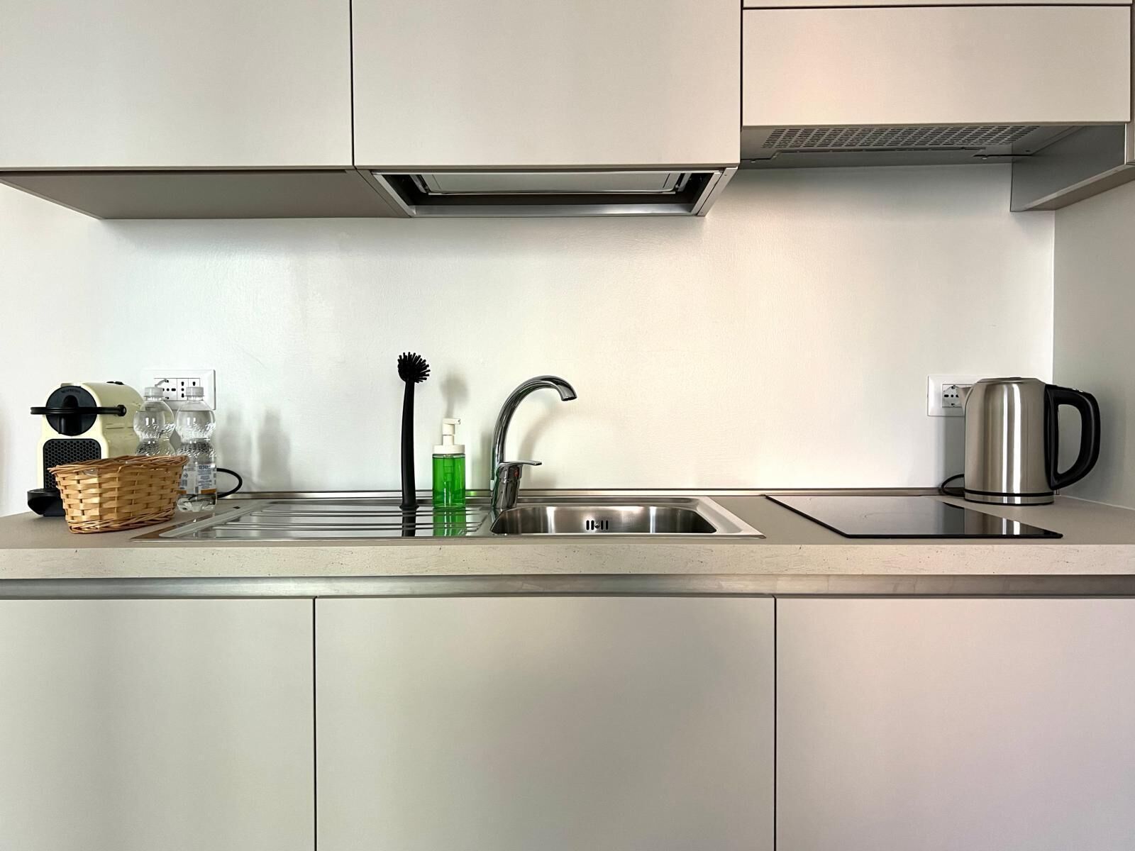 Eine moderne Küche mit Spüle aus Edelstahl, einem Wasserkocher und einer Obstschale.