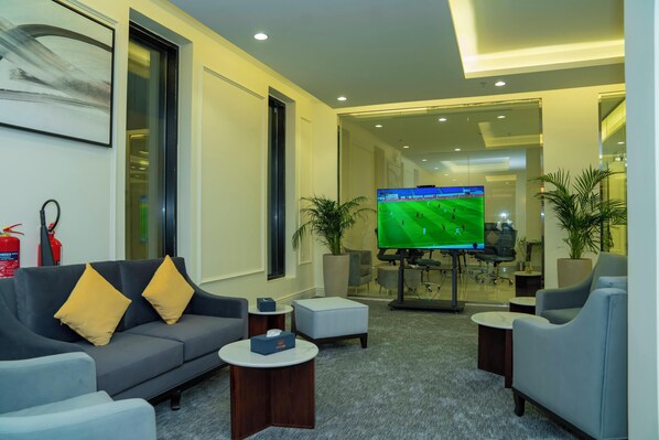 Una sala de estar moderna con un sofá gris, cojines amarillos, un televisor de pantalla plana y una mesa de centro.