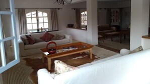 A living room with a white sofa, a wooden coffee table, and a chandelier.