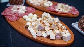 A wooden board with various cheeses and cured meats.