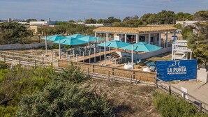 Un restaurante frente a la playa con mesas al aire libre y un letrero que dice "LA PUNTA PROSCIUTTO".