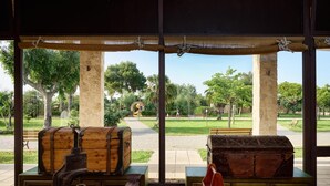 A view from a covered area with two wooden chests and a metal object on a table. - Torre Rinalda Beach Camping Mobilehome Happy Superior for 6 people (Lecce)