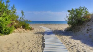 A sandy beach with a wooden pathway leading to the water. - Torre Rinalda Beach Camping Mobilehome Happy Superior for 6 people (Lecce)