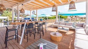 Une terrasse extérieure avec des tables, des chaises et un canapé en bois.