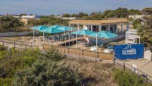 Un restaurant situé en bord de mer, avec une terrasse et une enseigne indiquant « LA PUNTA PROSCIUTTO ».