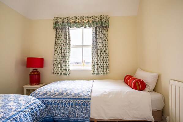 Une chambre à coucher avec un lit, une table de chevet avec une lampe et une fenêtre avec des rideaux.