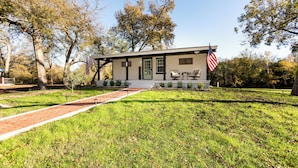 A small, single-story building with a front porch, two American flags, and a brick pathway leading to the entrance.