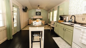 A kitchen with a central island, green cabinets, a white stove, and a dining area with a table and chairs.