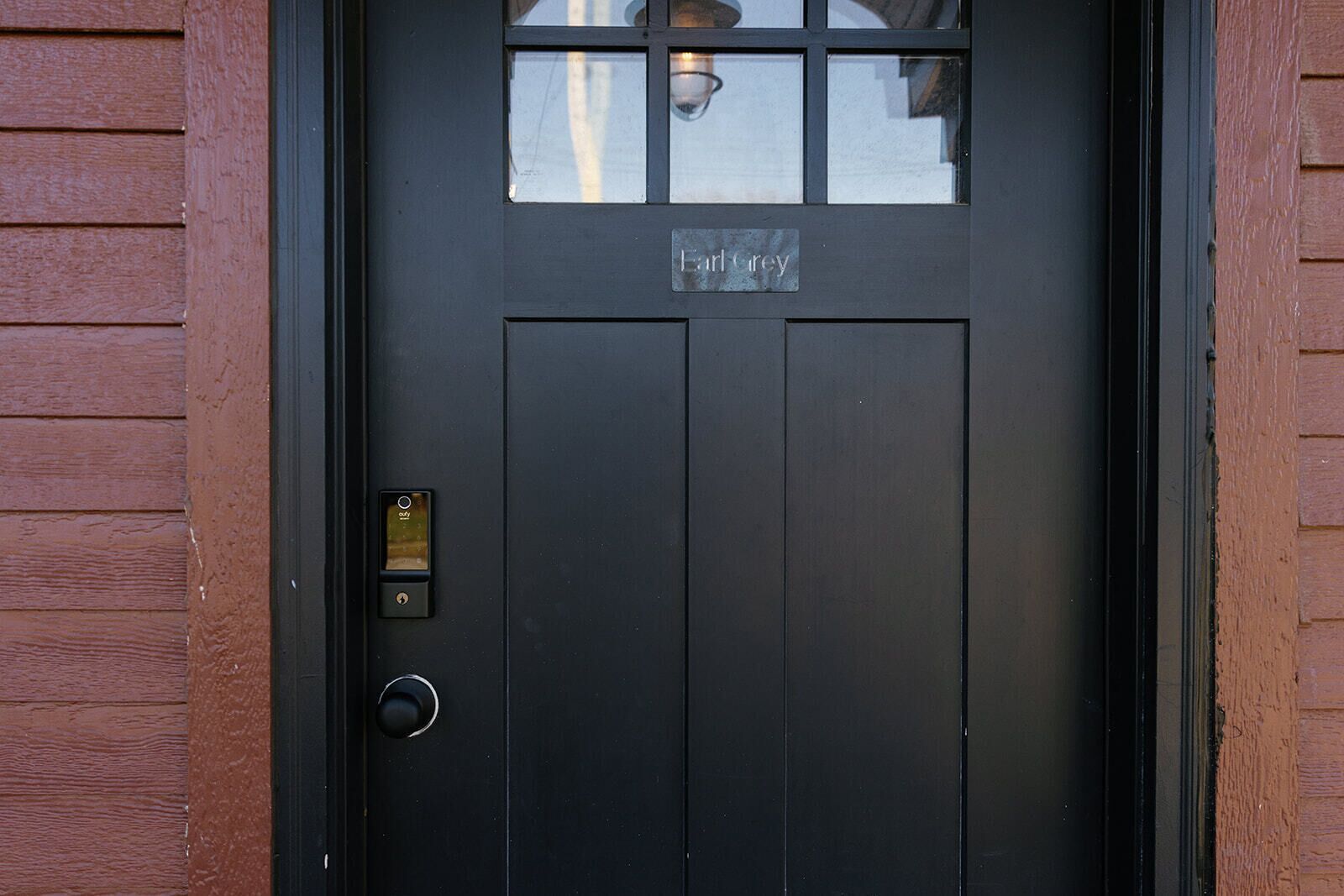 Une porte noire avec une plaque portant le nom « Earl Grey » et une serrure à clé.