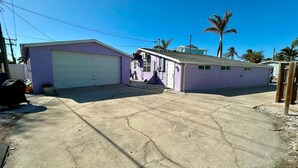 A two-story house with a garage, a small porch, and a driveway. - Lil Lavender House in Fort Myers Beach (Fort Myers Beach)