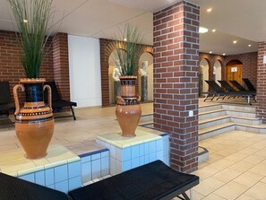 Step into a classic lobby with a seating area, decorative vases, and a historic staircase.