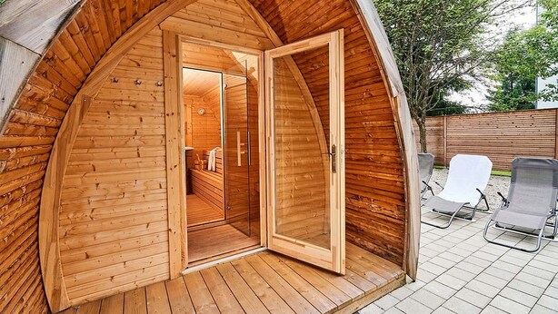 A wooden cabin with an open door leading to a bathroom and a patio area with two sun loungers. - 2 room family apartment "Vier Jahreszeiten" (Sankt Englmar)