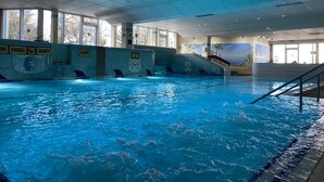 An indoor swimming pool with clear water, tiled walls, and windows allowing natural light. - 2 room family apartment "Vier Jahreszeiten" (Sankt Englmar)