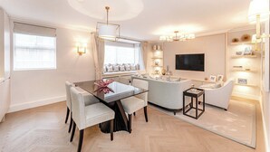 Ein modernes Wohnzimmer mit Essbereich, einer Couch, einem Fernseher und dekorativen Regalen.