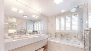 Ein modernes Badezimmer mit großem Spiegel, zwei Waschbecken, einer Badewanne und einer Dusche.