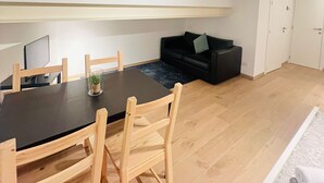 A modern living space with a dining area, a black sofa, and a wardrobe.
