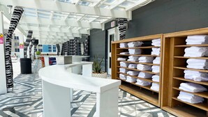 Un hall d'hôtel comprenant un comptoir d'accueil, un grand miroir et un mur avec des étagères remplies de serviettes pliées.