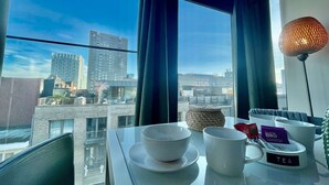 A table with tea cups and a tea kettle in a room with a city view. - Cozy 1BR City Centre Near Meir Shopping by Oneluxstay (Antwerp)