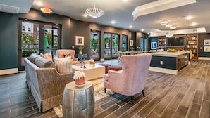 A modern living room with a sofa, armchairs, and a coffee table. There is a kitchen area with a dining table and chairs.