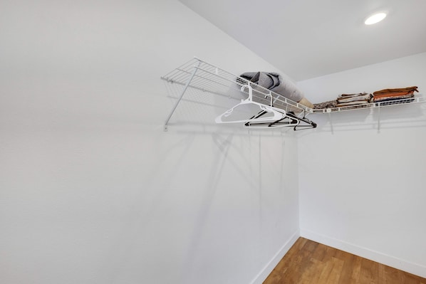A room with a white wall, a wooden floor, and a ceiling-mounted drying rack with clothes. - Stylish 2BR Family Apartment by Dtla (Los Angeles)