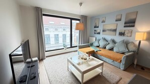 A modern living room with a sofa, a coffee table, and a TV. - Spacious 3BR 2/5 BA Near Diamond District by Oneluxstay (Antwerp)
