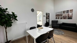 A modern living room with a white table, black chairs, a grey sofa, and a large mirror. - Luxury 1BR Near Fashion District by Oneluxstay (Antwerp)