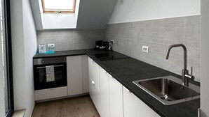 A modern kitchen with a skylight, black countertops, and white cabinetry. - Luxury 1BR Near Fashion District by Oneluxstay (Antwerp)