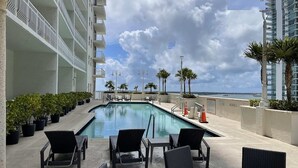 A pool area with lounge chairs and potted plants, overlooking a body of water. - Modern 1BR At Brickell Bay Club by Oneluxstay (Miami)
