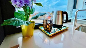A kitchen counter with a coffee maker, a potted plant, and a tray with oranges. - Modern 2BR Penthouse Near Diamond District by Oneluxstay (Antwerp)