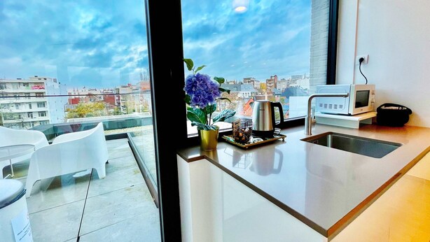 A modern kitchen with a large window, a coffee maker, and a kettle on the counter. - Modern 2BR Penthouse Near Diamond District by Oneluxstay (Antwerp)