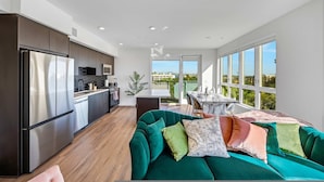 A modern kitchen with a large refrigerator, wooden flooring, and a view to the outside. - Luxury 2BR Hollywood Pool View by Oneluxstay (Los Angeles)