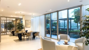 A modern interior with a dining area, sofas, and large windows offering a view of the city. - One Lux Stay Grande Signature Residences (Dubai)
