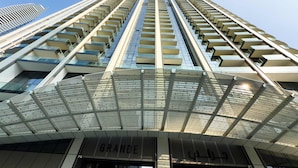 A high-rise building with multiple balconies, a glass facade, and a modern architectural design. - One Lux Stay Grande Signature Residences (Dubai)