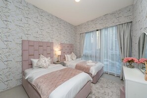 Un dormitorio con dos camas, una mesita de noche, un espejo y una ventana con cortinas.