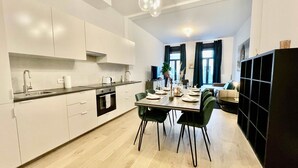Eine moderne Küche mit weißen Schränken, einer schwarzen Arbeitsplatte und einem Essbereich mit Tisch für vier Personen.