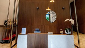 En reception med træbeklædt væg, et rundt spejl og hængende pendellamper.