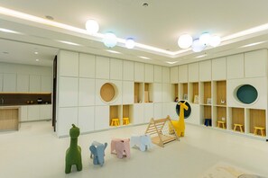 A modern children's play area with built-in storage, a play structure, and a kitchen area.